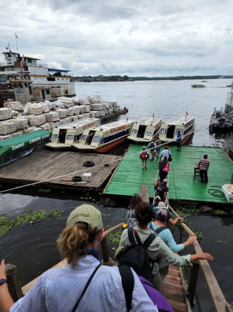 A group of people standing on the dock near boats.